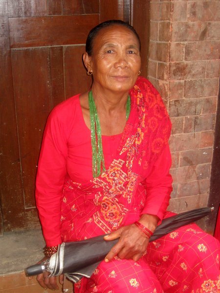Lady wearing traditional red sari and green beads
