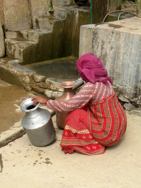 Lady wearing traditional dress washing milk urns