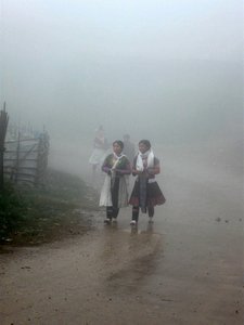 Young girls walking in fog along mountain road near Sin Ho