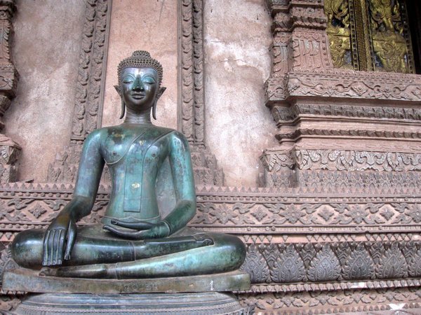Bronze Buddha and wall carvings at Haw Pha Kaeo