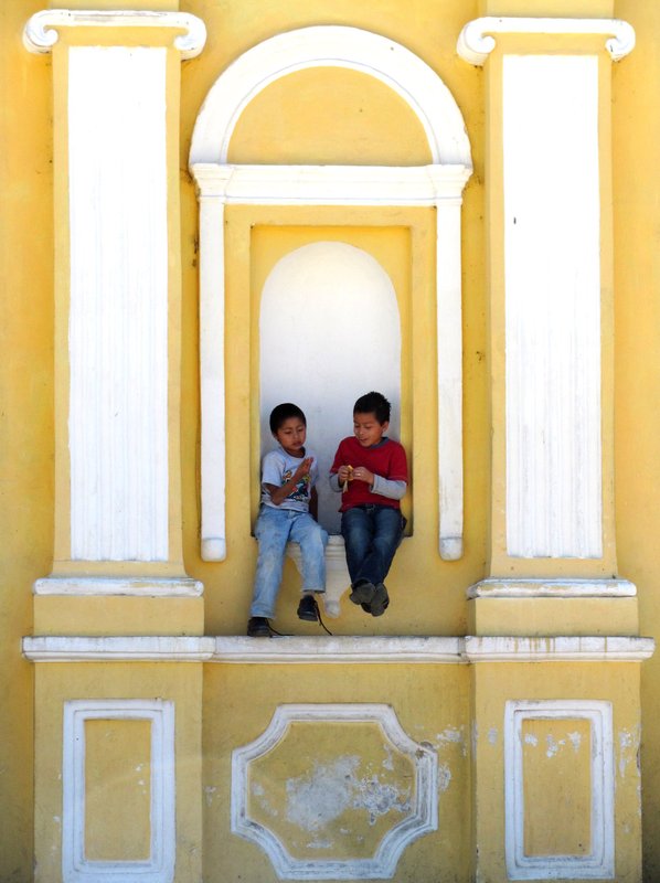 Schoolboys sitting on niche in church, San Pedro village