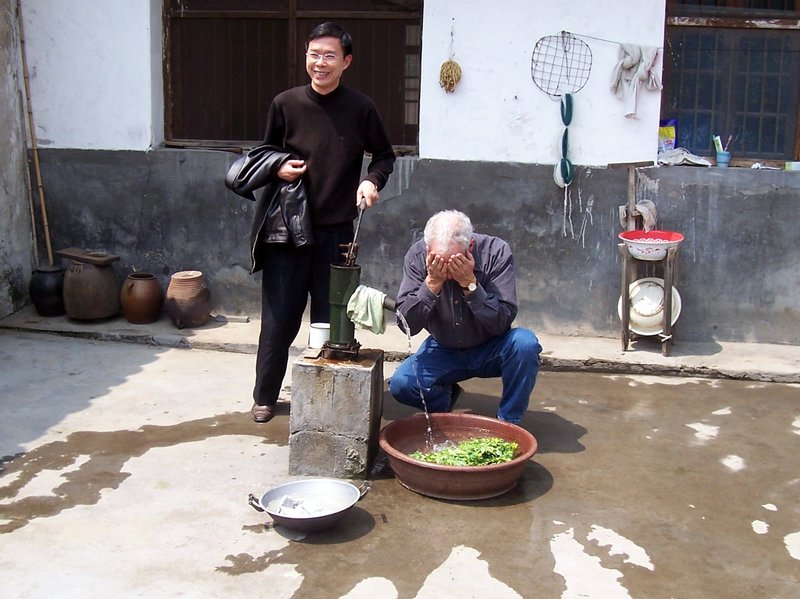 Jerry and our headmaster pumping water in village house courtyard