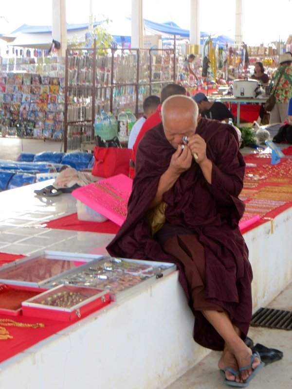 Monk closely checking Buddha images at the market