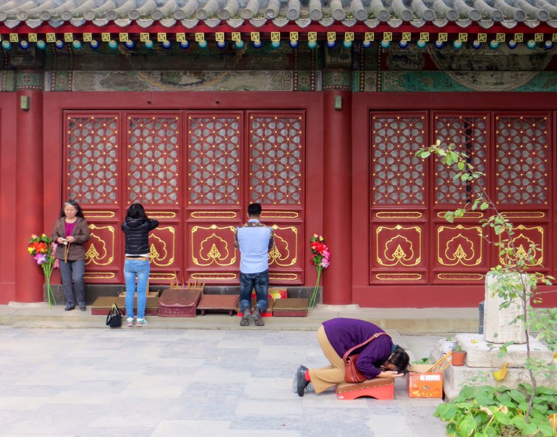 Praying to locked doors of a hall which enclose a large reclining Buddha at the Fayuan Temple.
