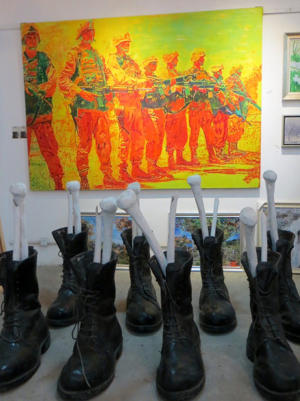 Painting of American soldiers behind a display of army boots and leg bones...