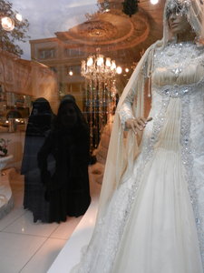 Covered women inspecting wedding dresses