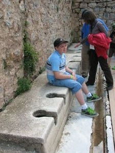 Liam sitting on an Ancient Toilet