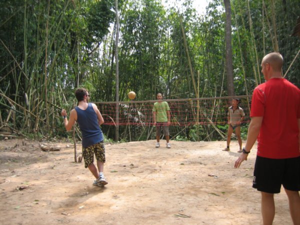 3 of the boys playing with a lao guy . Volleyball with the feet