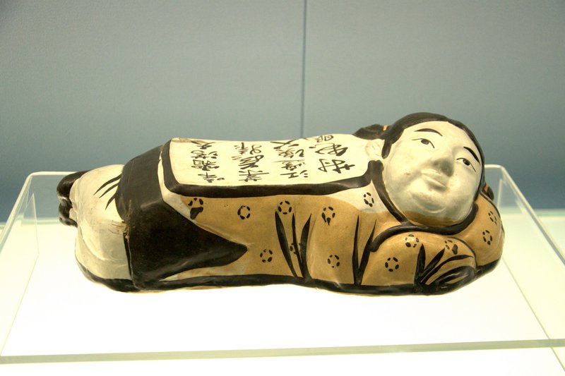 Child-shaped pillow with black designs on a white ground
