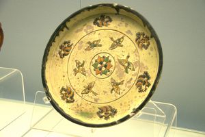 Polychrome-glazed pottery dish with three feet and moulded bird and cloud design