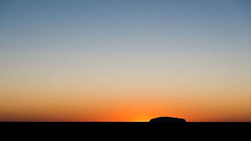 Sun rising from behind Uluru