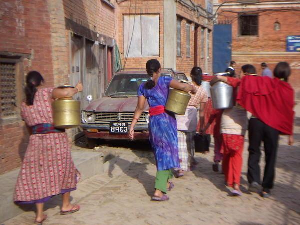 Women carrying water holders thru the streets of Patan