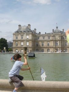 Little French boy sailing his boat on the pond at Luxembourg Jardins
