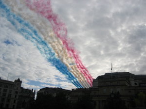 Smoke streams after the Red Arrows fly over Trafalgar Square towards Buckingham Palace
