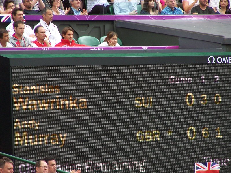 Roger Federer and his wife sitting above the scoreboard