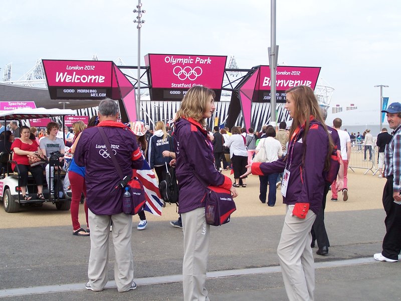 Cheerful and Helpful Olympic volunteers in the Olympic colors of pink, purple, and orange