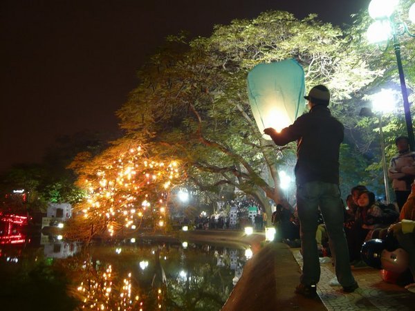 Tourist releasing a candle lantern on Hoan Kiem Lake