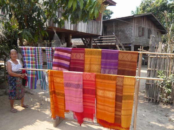 Village woman displaying her home-woven fabrics for sale