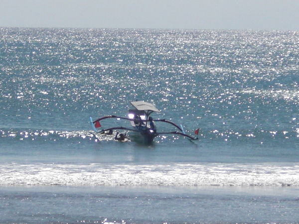 An Outrigger with a surfer on the side... not exactly sure what they were doing but it looks like they are both about to catch the same wave