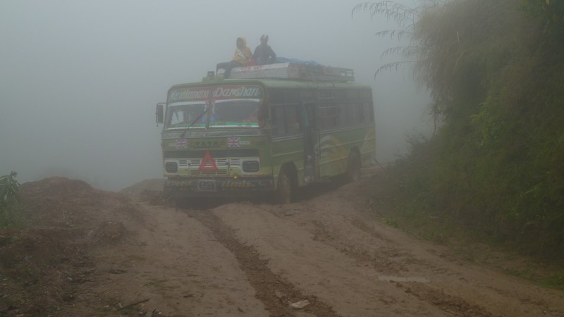 A bus appears in the fog and mud