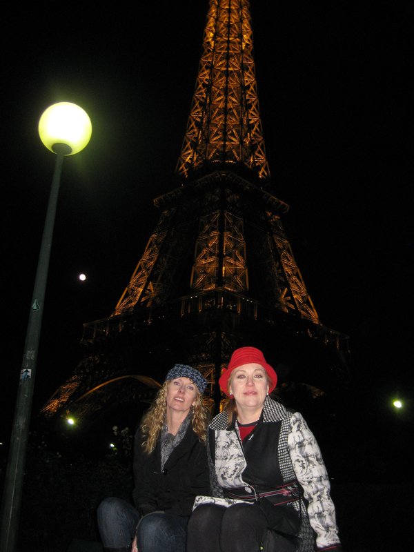 Charlene and Brandee at the Eiffel Tower at night.