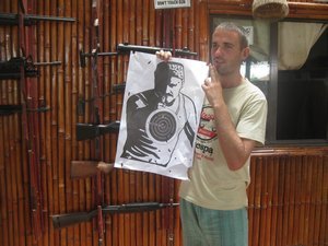 39. Mike proudly shows off his target after he has peppered it with 30 AK-47 bullets, a shooting rang near Phnom Penh