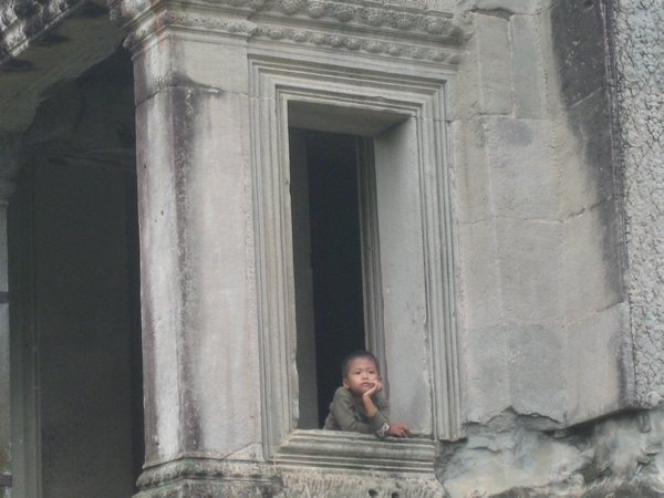 89. A Khmer boy stares out of one of the windows in the outer galleries of Angkor Wat