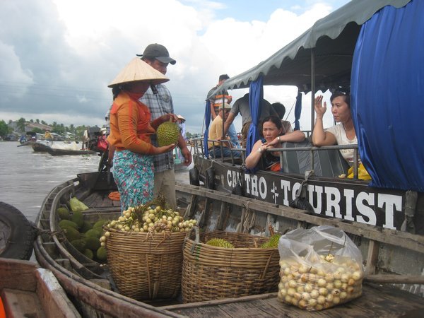 17. A trader tries to sell a durian  to tourists at Cai Rang floating market, Mekong Delta