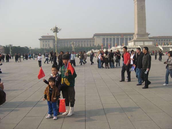 3. Some Chinese kids posing for a photo holding Chinese flags in Tiananmen Square, Beijing