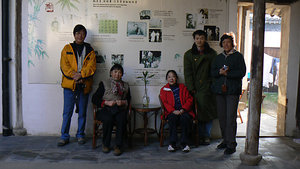 the owner of the hostel, standing in the green coat by family tree of his ancestors 