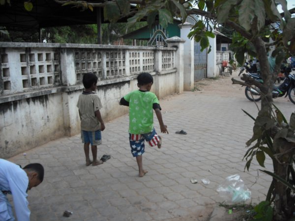 Kids playing a game that involved kicking flip-flops down the sidewalk