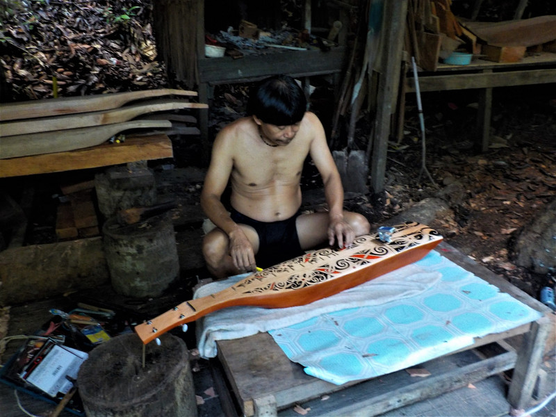 Stringing a new Sape in the Penan hut