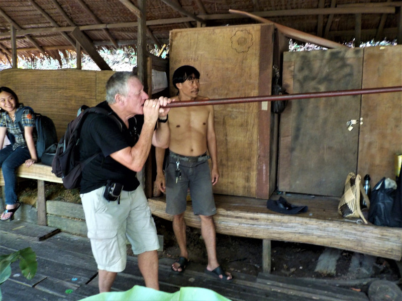 John blowing darts at cans in the Penan hut