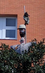 A scarecrow like figure outside apartment building in suburbs of  