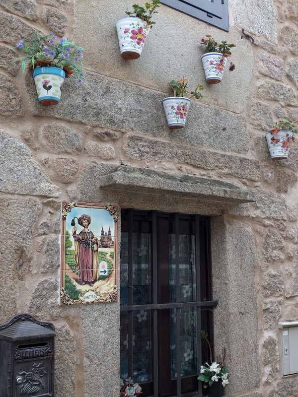 This house has colorful pots and a St James plaque on the wall