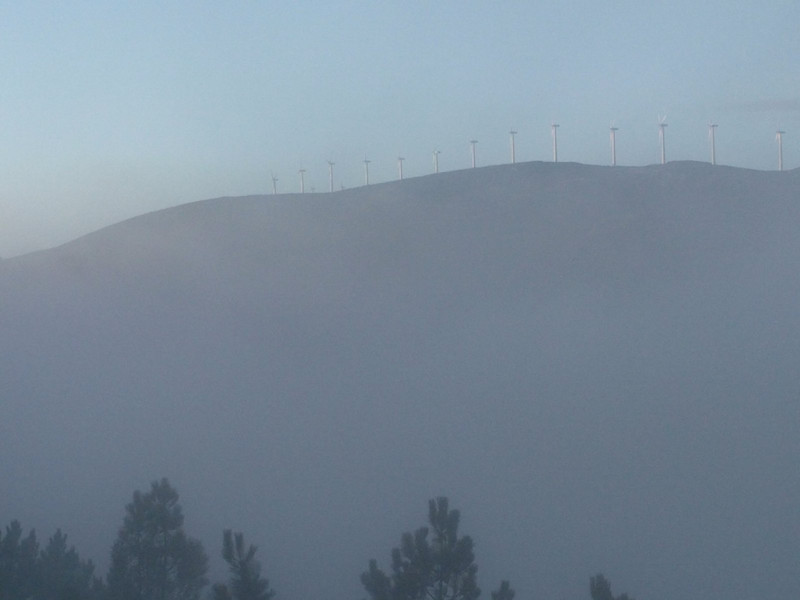A row of wind turbines line the crest of the hill