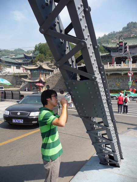 Een dappere jobstudent verft de brug met een tandenborstel.