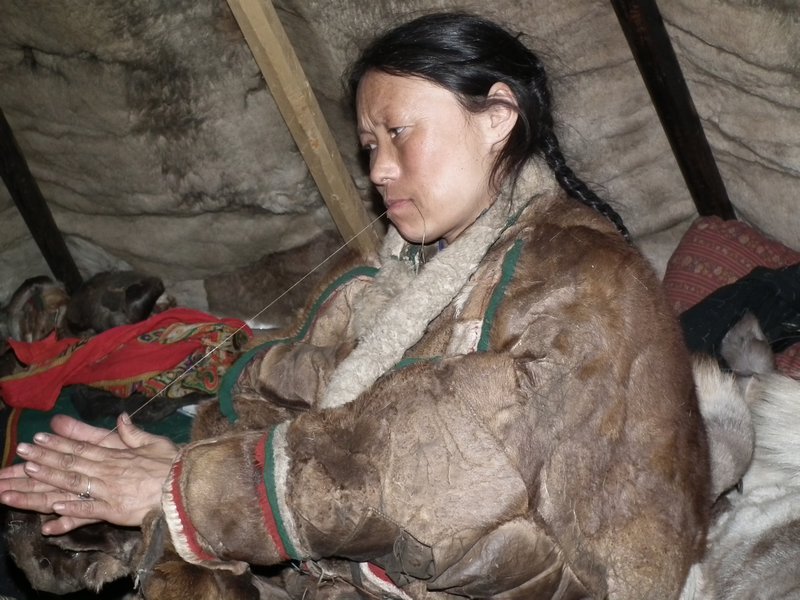 Sveta, a Nenets woman, making thread from reindeer sinew in her chum, Nadym Region, Siberia