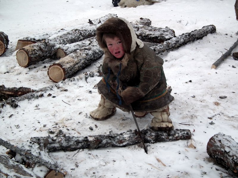 Nenets child playing with a saw at an encampment, Nadym Region, Siberia