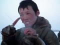 Myangche, a Nenets boy, eating raw meat straight from a reindeer carcass, Nadym Region, Siberia