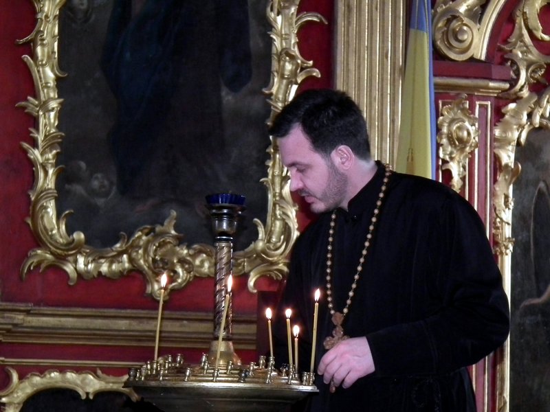 Priest lighting candles in Andreevskaya Church, Kiev, Ukraine