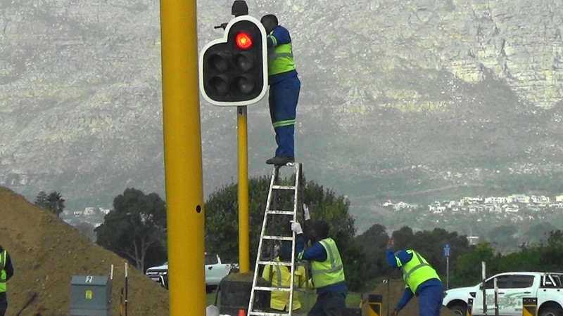 Road worker on top of a ladder maintaining the traffic light without a harness or any safety gear,O M G