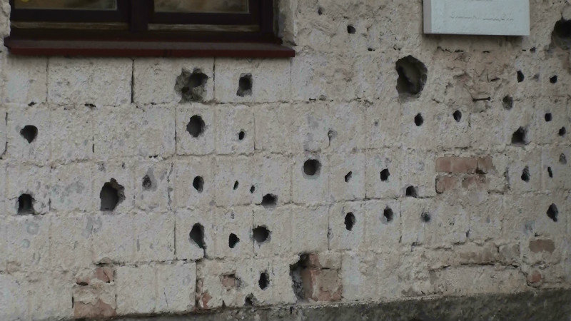 Bullet and shrapnel holes in the plaster walls of the house
