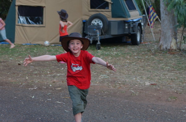 Joey kicking the footy with other kids at the campsite