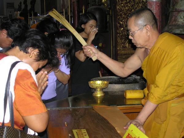 Buddhist monk giving blessing of holy water to Thai before they leave the temple