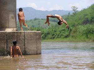 Children jumping off a bridge to cool off as we pass in our boat
