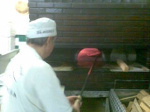 The chef skillfully rotating the pizza inside the oven using the pizza board
