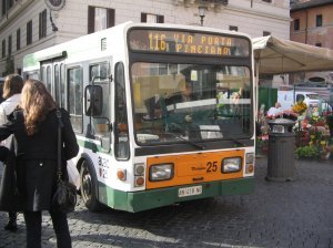 A small bus navigating through the crowds in Campo de Fiori