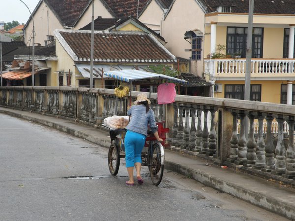 A street vendor crossing a bridge in Hoi An