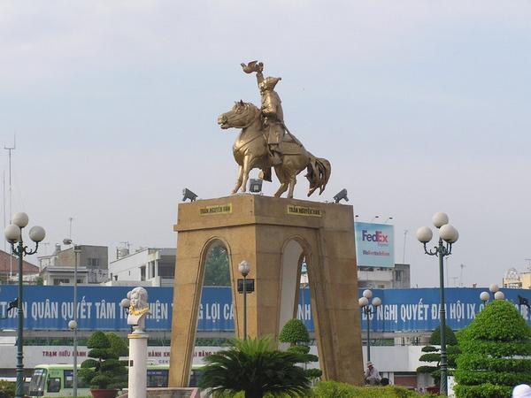 A golden statue of a Vietnamese hero in front of Ben Thanh Market